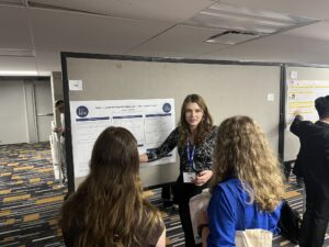 Juniper Creskoff presents research poster to an audience