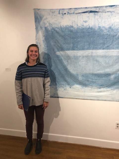 Image shows student standing with her artwork