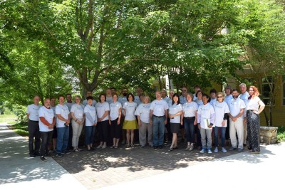 Image shows group of people standing in front of a tree in matching white t-shirts