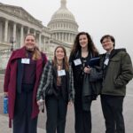 Students pose outside on the steps of the capitol with the capitol dome in the background