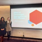 Students and faculty in front of screen at conference presentation