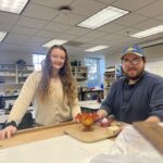 2 students at a table standing behond some artifacts in the archology lab