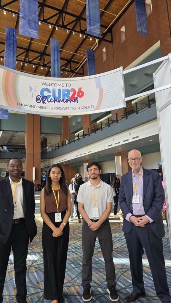 3 computer science students and their professor under the banner at NCUR