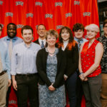 Photo of the UMW Debate Team Posing against UNLV Backdrop with Coach Adrienne Brovero