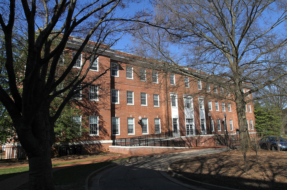 Image of Combs Hall, a three-story brick building against a blue sky.