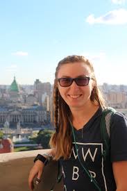 Portrait of Krista Beucler with a UMW Study Abroad t-shirt posed against a cityscape in the background.