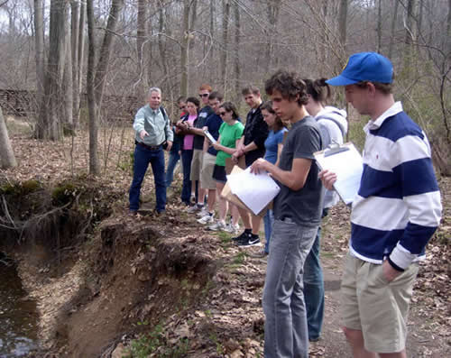 Students observe fluvial erosion along Hazel Run in Alum Spring Park, with Dr. Joseph Nicholas.