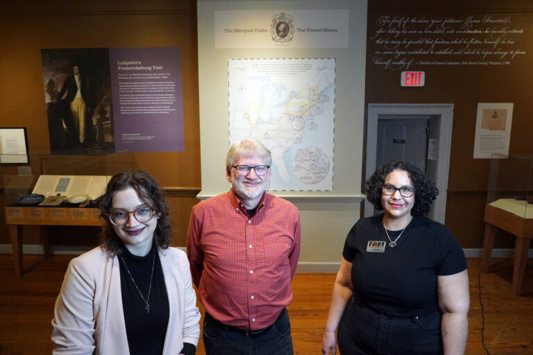 Brooke, Dr. Hanna & Gaila Sims stand in front of Lafayette map, FAM