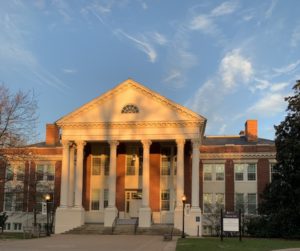 Monroe Hall with sunlight reflecting off of it. There is also the Monroe Hall sign in front and ASPIRE banners on the lamps.