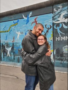 Gabriel Matteson hugging another student in front of The East Side Gallery in Berlin.